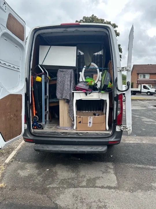 House removals van loaded with vanity, cabinets, and a hand truck secured with ratchet straps and bungee cords for a UK home move