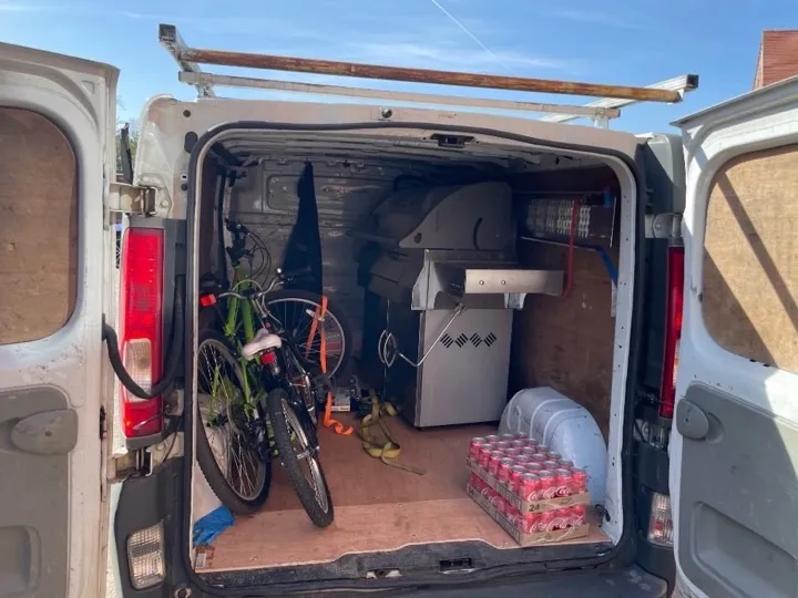 White delivery van loaded with bicycles and a stainless steel gas grill for household item collection and delivery