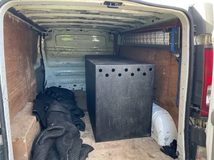 Specialist crate secured inside a removals van with moving blankets and tie-down straps for a careful small-move delivery