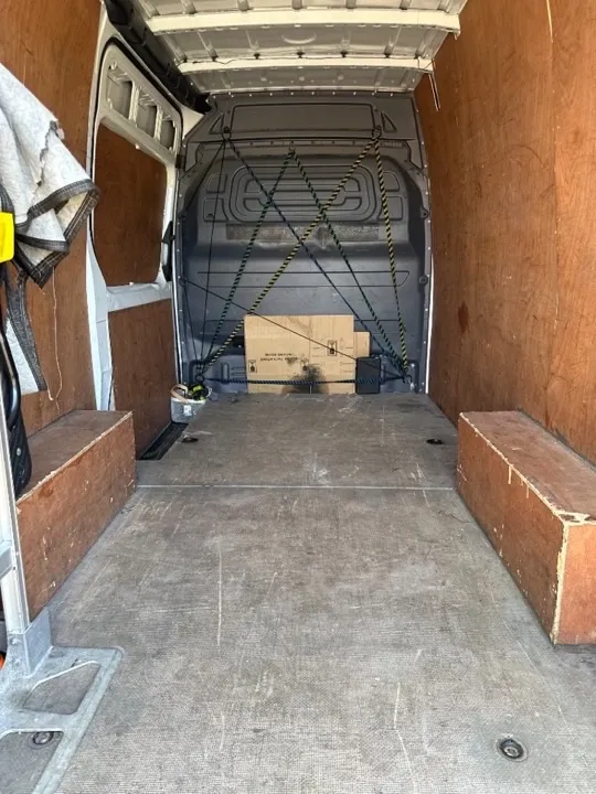 Storage solutions — secure transit van interior Plywood-lined removals van interior with tie-down straps securing items for safe transport to storage facilities